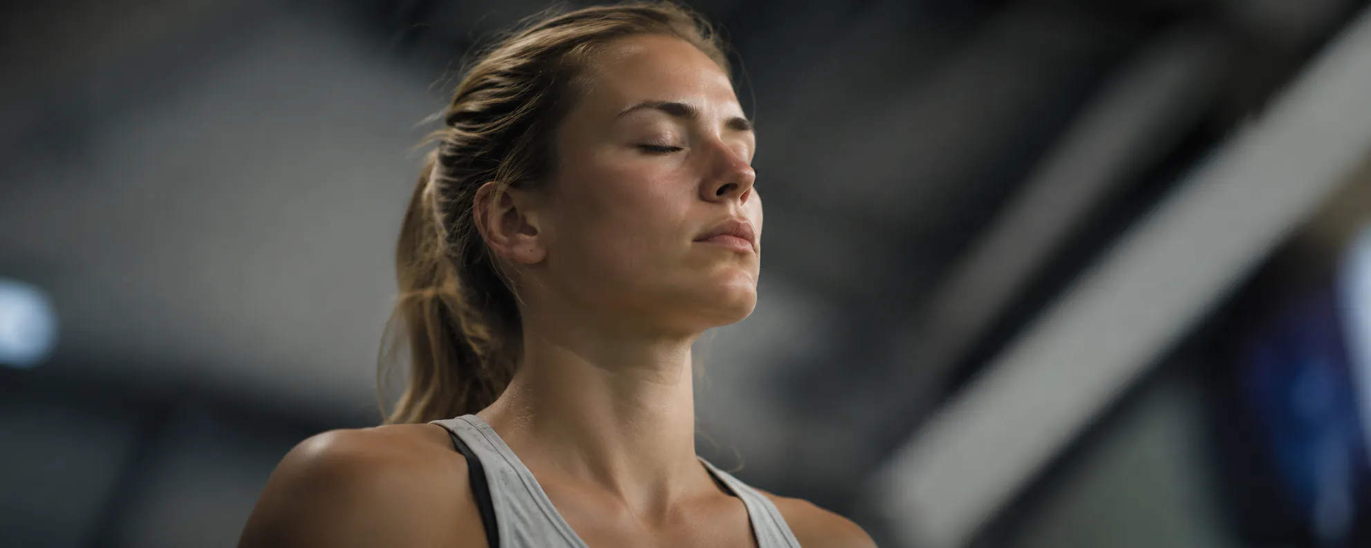 Sportlerin mit geschlossenen Augen visualisiert konzentriert vor dem Wettkampf in der Halle – Symbolbild Spitzenleistungsanker durch Hypnose in Augsburg
